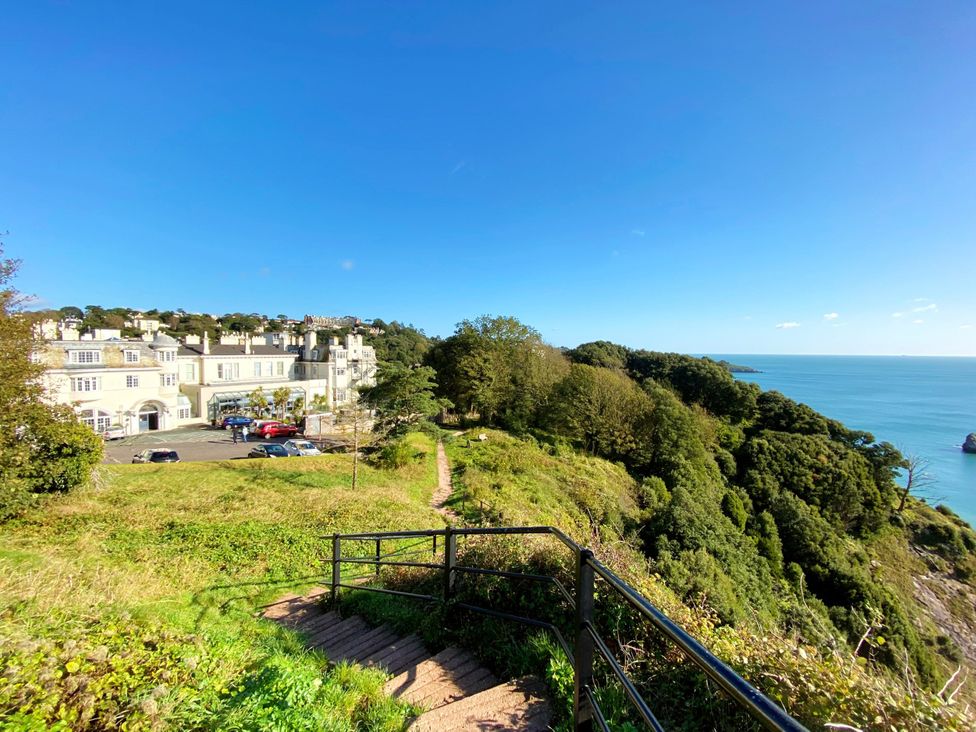 A building near a pathway and ocean at Lower Stable - The Stables Apartments at Meadfoot Bay Torquay