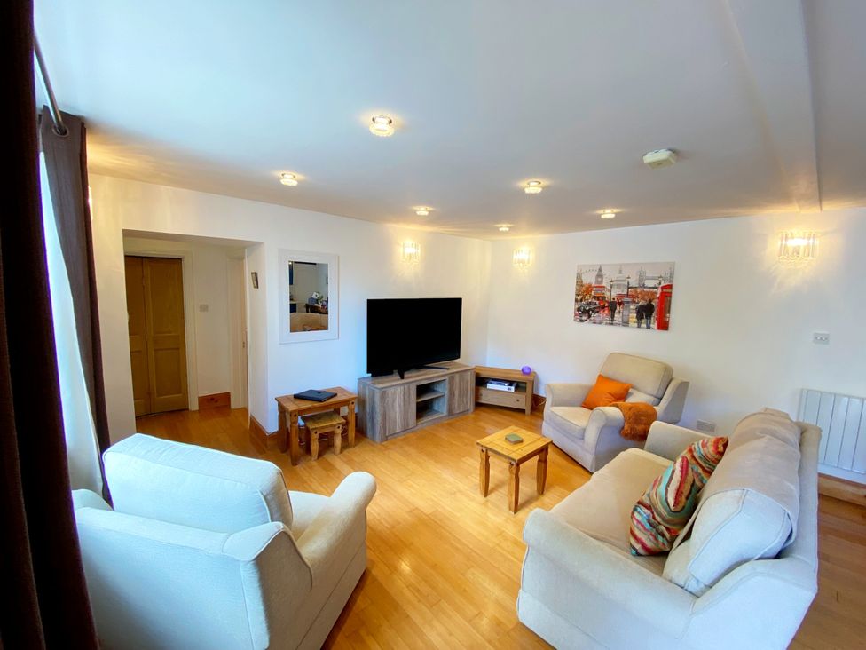 A living room with a television and sofa at Lower Stable - The Stables Apartments at Meadfoot Bay, Torquay