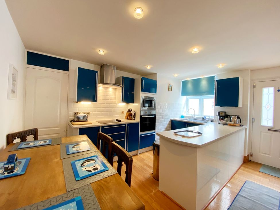 A kitchen with appliances and dining table at Lower Stable - The Stables Apartments at Meadfoot Bay, Torquay