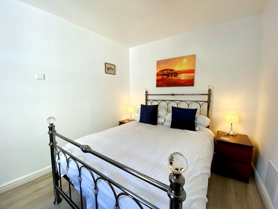 A bedroom with a bed and bedside table at Lower Stable - The Stables Apartments at Meadfoot Bay, Torquay