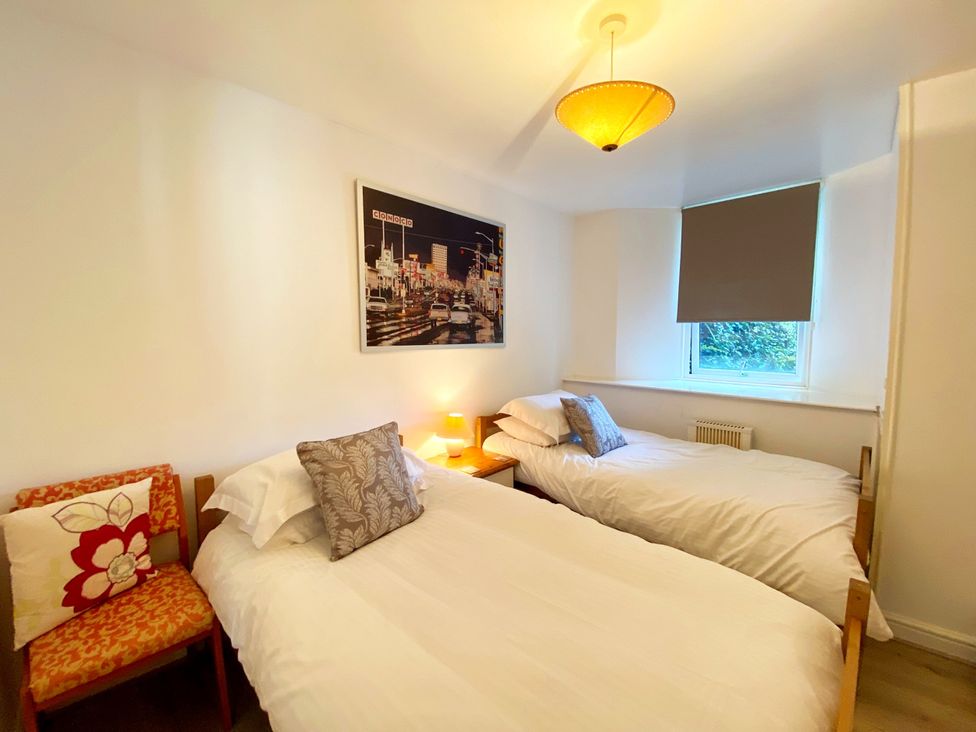 A bedroom with twin beds and a chair at Lower Stable - The Stables Apartments at Meadfoot Bay Torquay