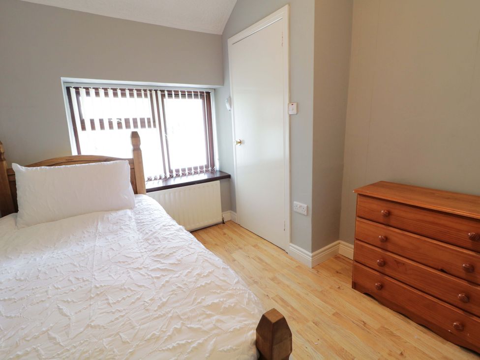 A bedroom with a bed, dresser, and window at 4 Bed Property in Northern Ireland