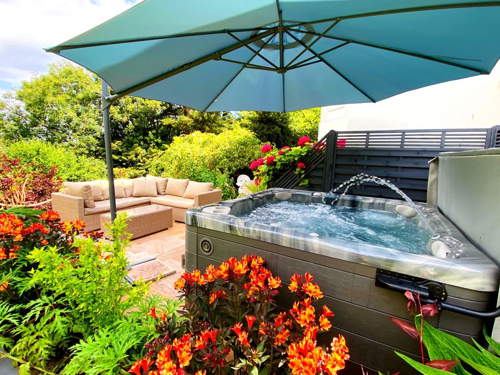 A garden with a hot tub and outdoor sofa at Muntham Luxury Town House with Hot Tub in Torquay