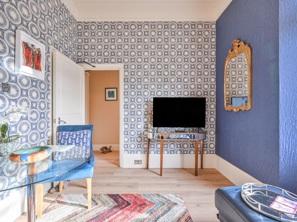 A living room with a glass table and blue chair at Muntham Apartment 4 in Torquay