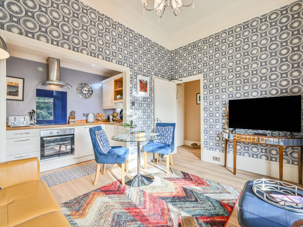 A kitchen with a dining table and television at Muntham Apartment 4 in Torquay