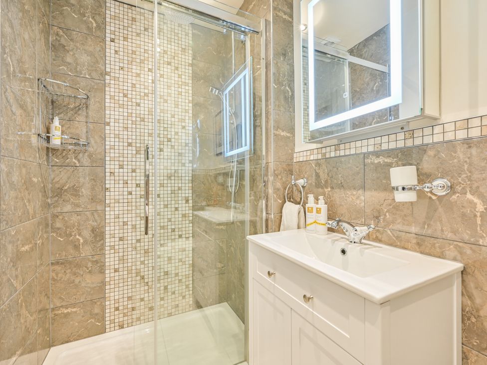 A bathroom with a shower, vanity, and mirror at Muntham Apartment 4 in Torquay