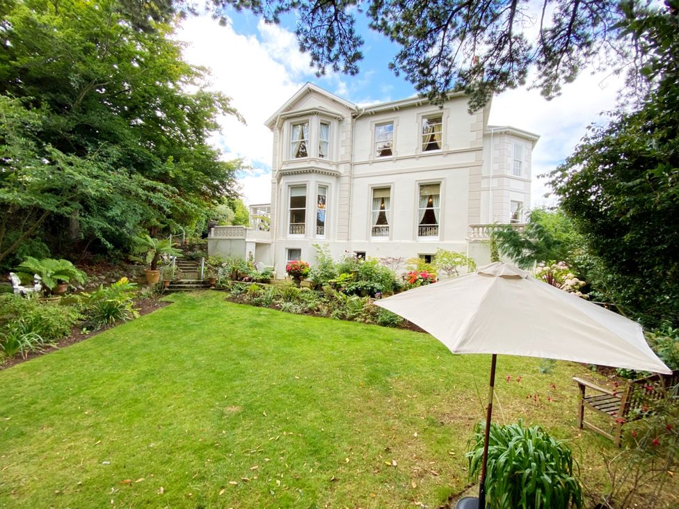 A house with a garden and umbrella at Muntham Studio Apartment 5 in Torquay