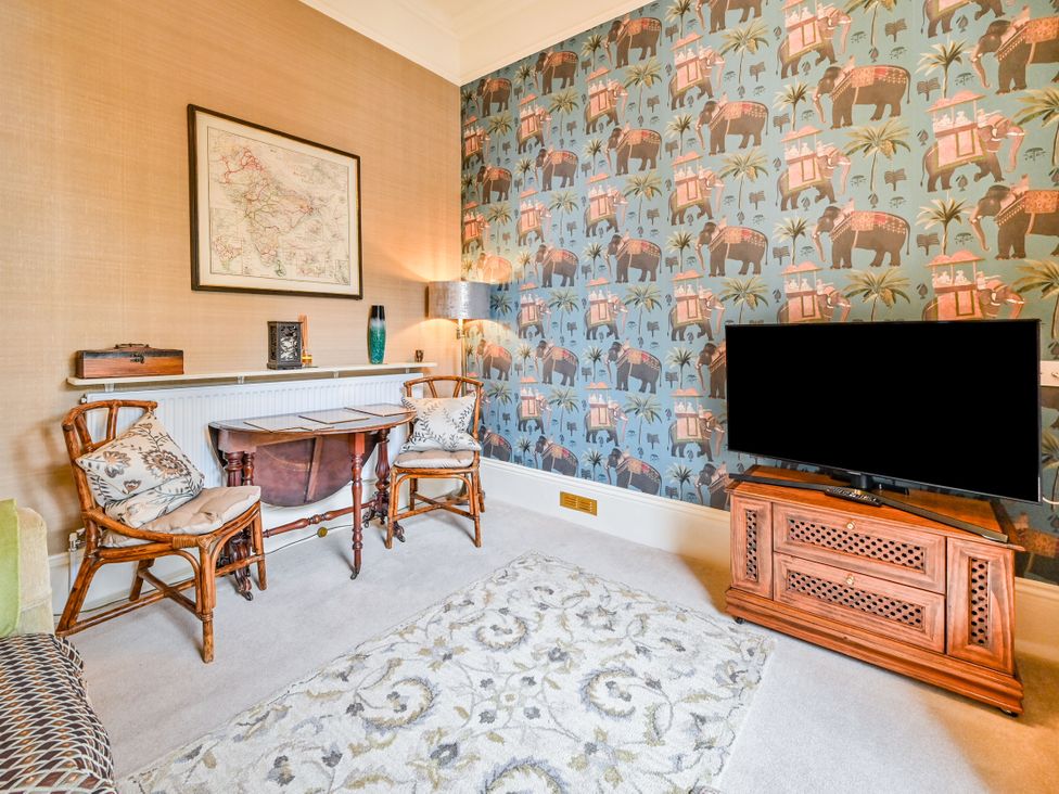 A living room with a rattan chair and television at Muntham Apartment 6 in Torquay
