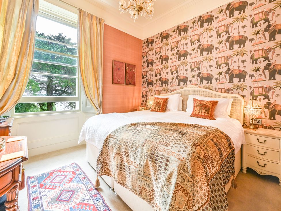 A bedroom with a large bed and patterned wallpaper at Muntham Apartment 6 in Torquay