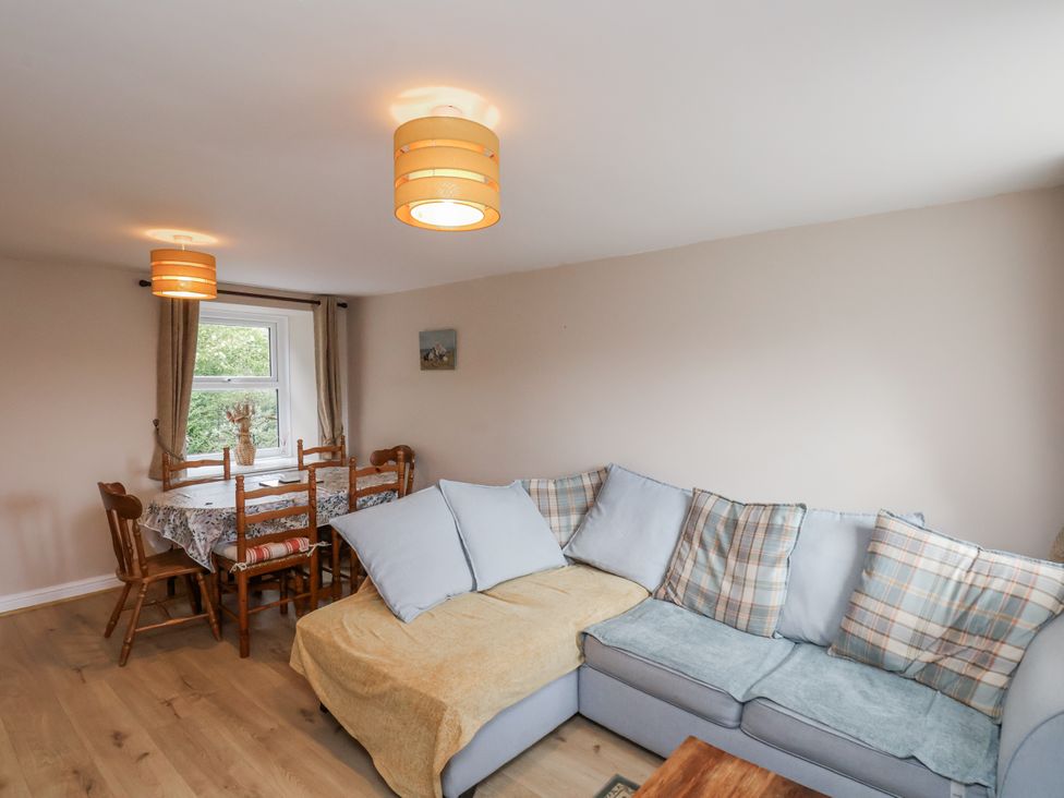 A living room with a sofa and dining table at Starlight Cottage