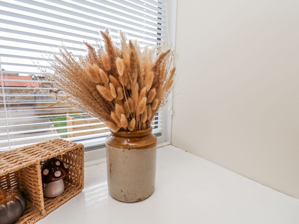 A vase with dried flowers and a woven basket at Starlight Cottage