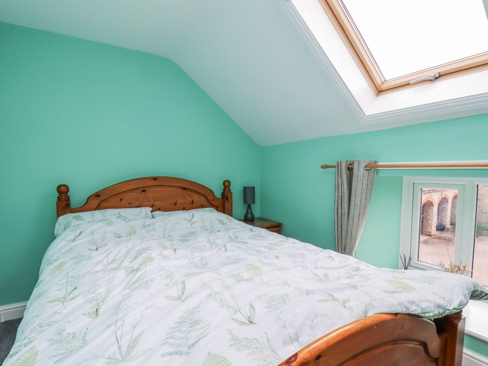 A bedroom with a bed and window at Starlight Cottage