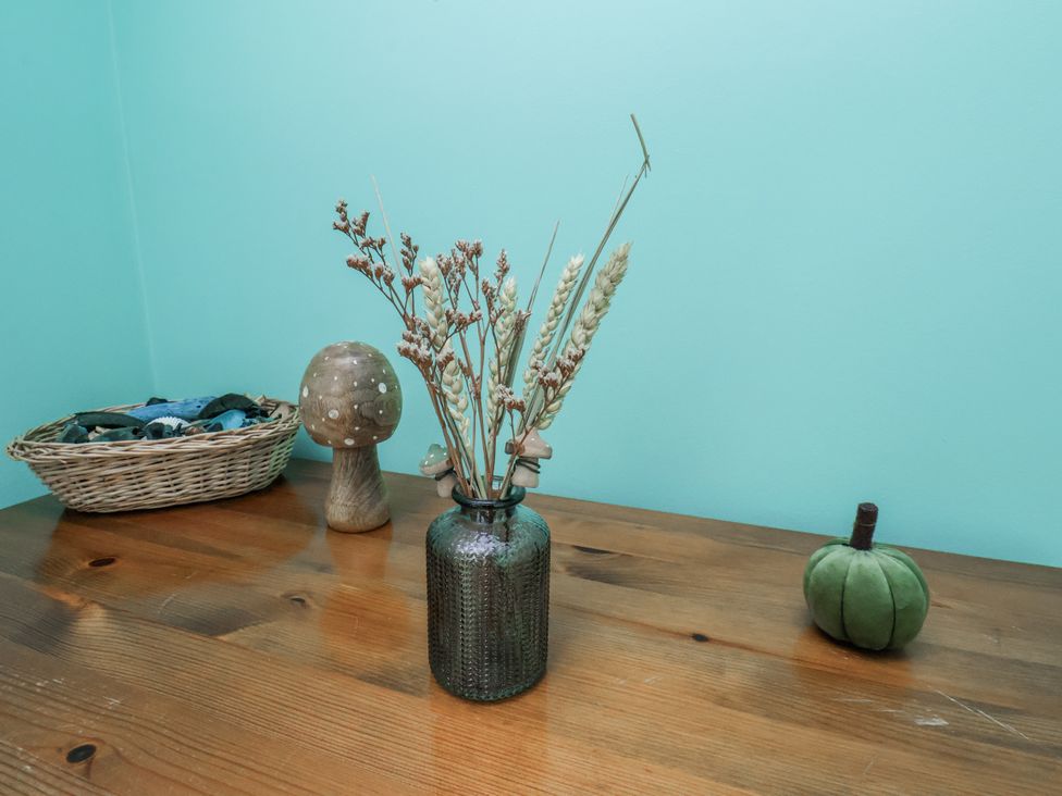 A table with dried flowers in a vase and decorative items at Starlight Cottage