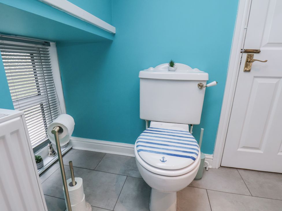 A toilet with a blue seat in a bathroom at Starlight Cottage