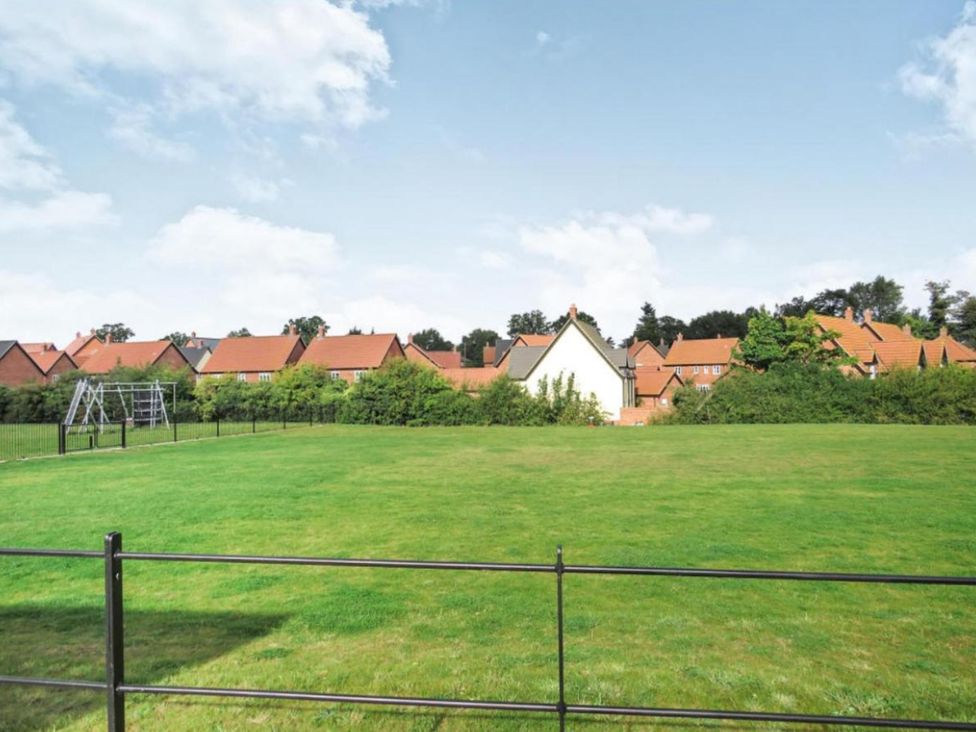 A grassy area with a playground and houses in the background
