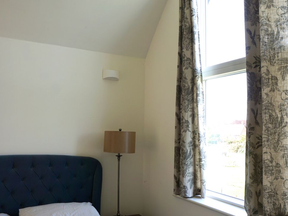 A bedroom with a bed, lamp, and curtains at 