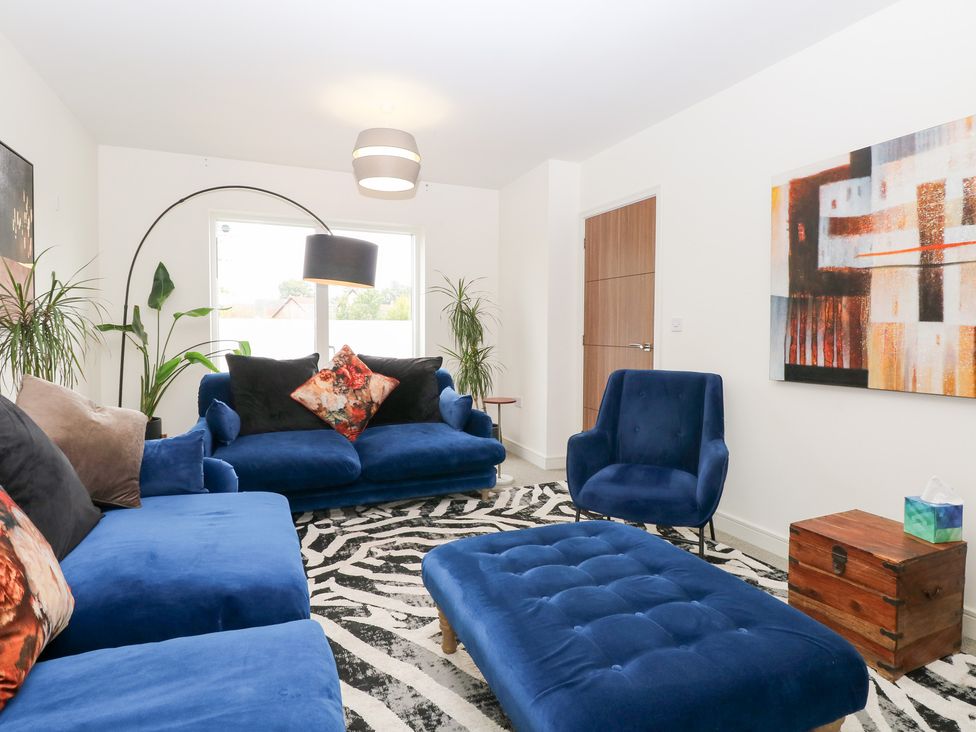 A living room with blue furniture and a painting at Manor Park View in Norwich