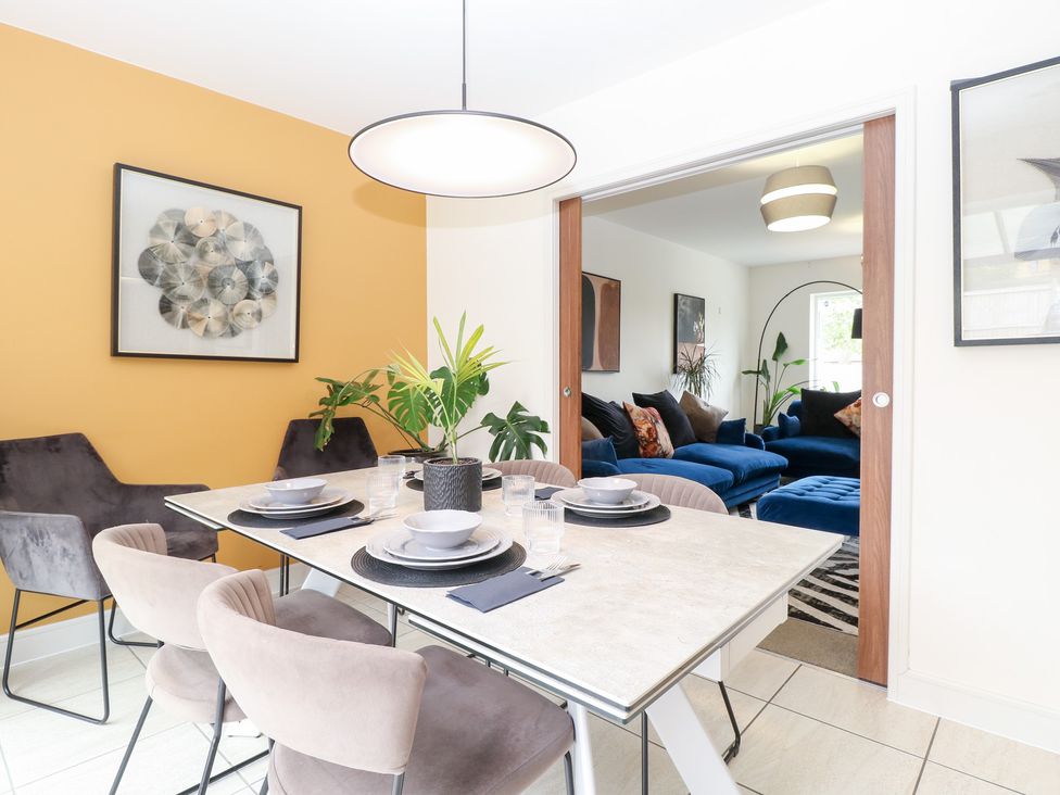 A dining room with a table and chairs overlooking a living room at Manor Park View in Norwich
