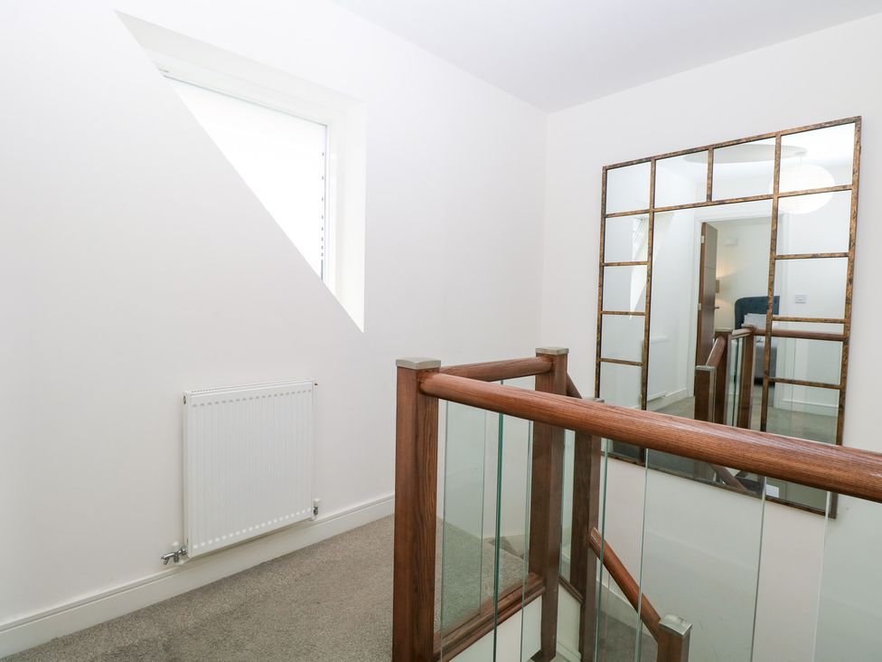 A hallway with a mirror and window at Manor Park View in Norwich