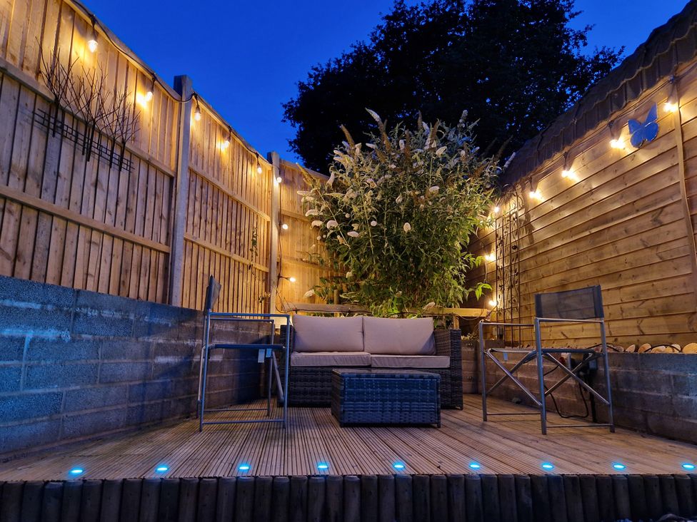 A garden with a seating area and plants at Honeysuckle Cottage in Smallridge