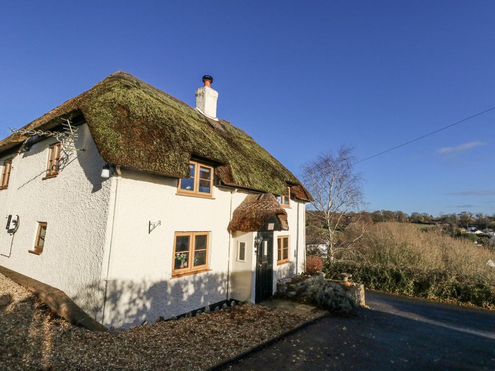 A house with a thatched roof and driveway at Honeysuckle Cottage in Smallridge Nr. Axminster