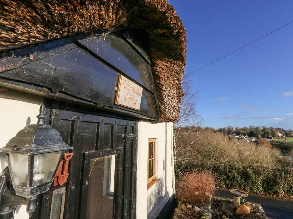 A cottage entrance with a thatched roof and sign at Honeysuckle Cottage Smallridge Nr. Axminster