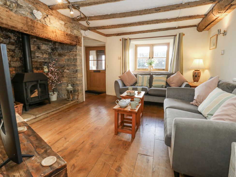 A living room with a stove and a table at Honeysuckle Cottage in Smallridge Nr. Axminster