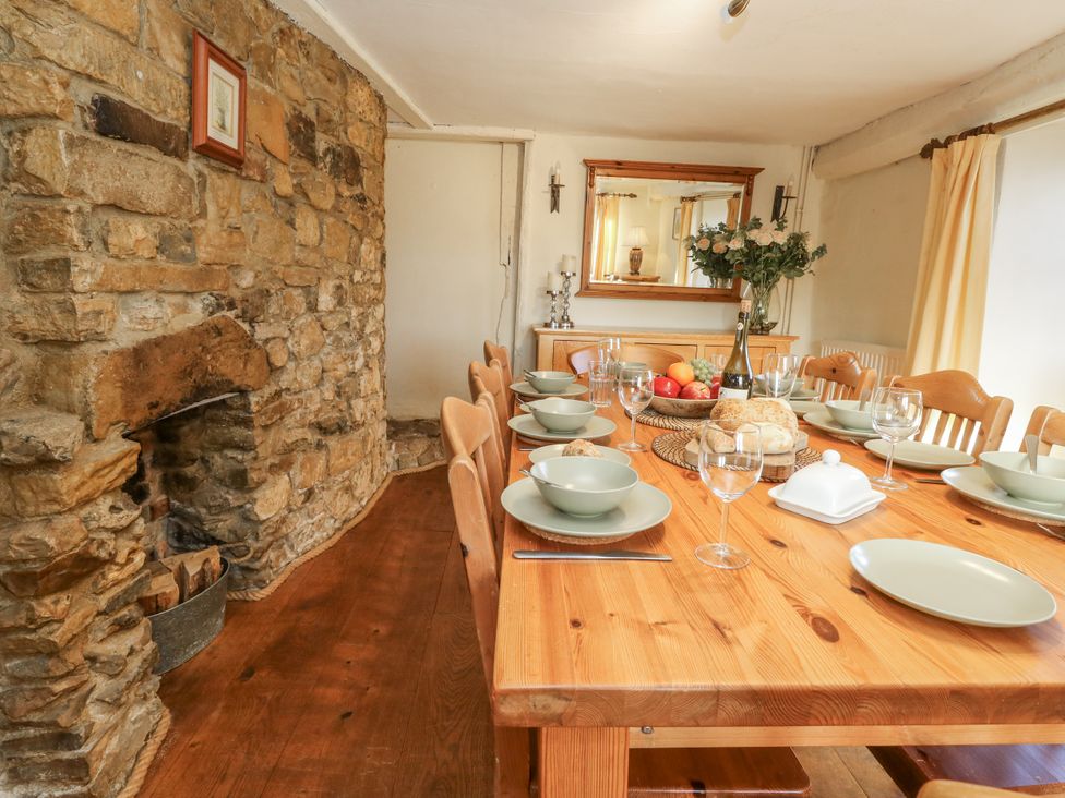A dining room with a wooden table set for a meal at Honeysuckle Cottage in Smallridge Nr. Axminster