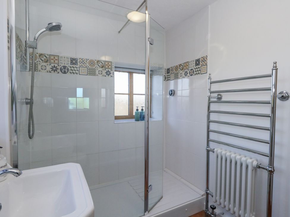 A bathroom with a shower and towel rack at Honeysuckle Cottage Smallridge Nr. Axminster