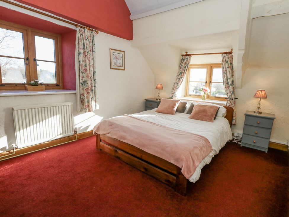 A bedroom with a bed and two windows at Honeysuckle Cottage Smallridge Nr. Axminster