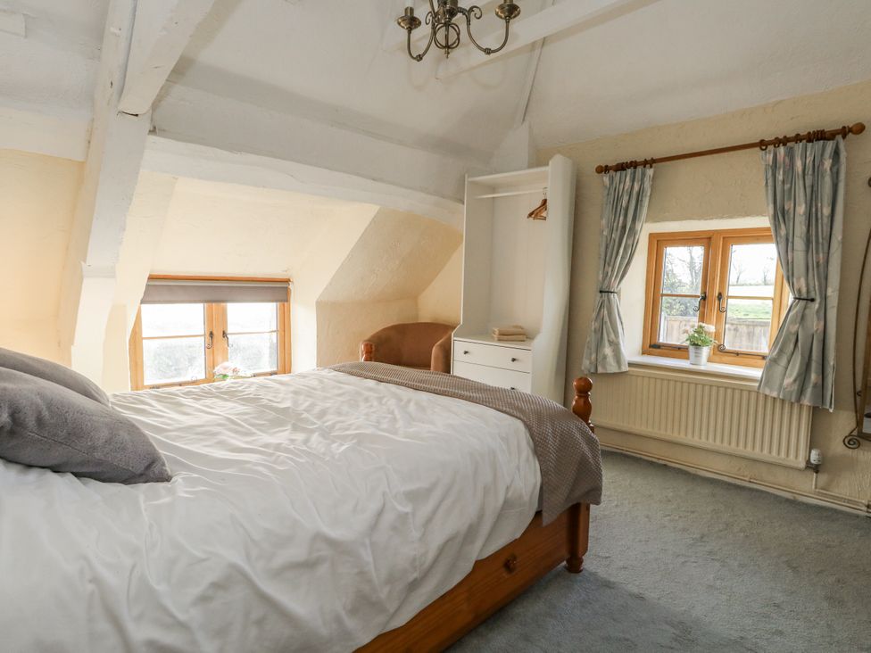 A bedroom with a bed and windows at Honeysuckle Cottage Smallridge Nr. Axminster