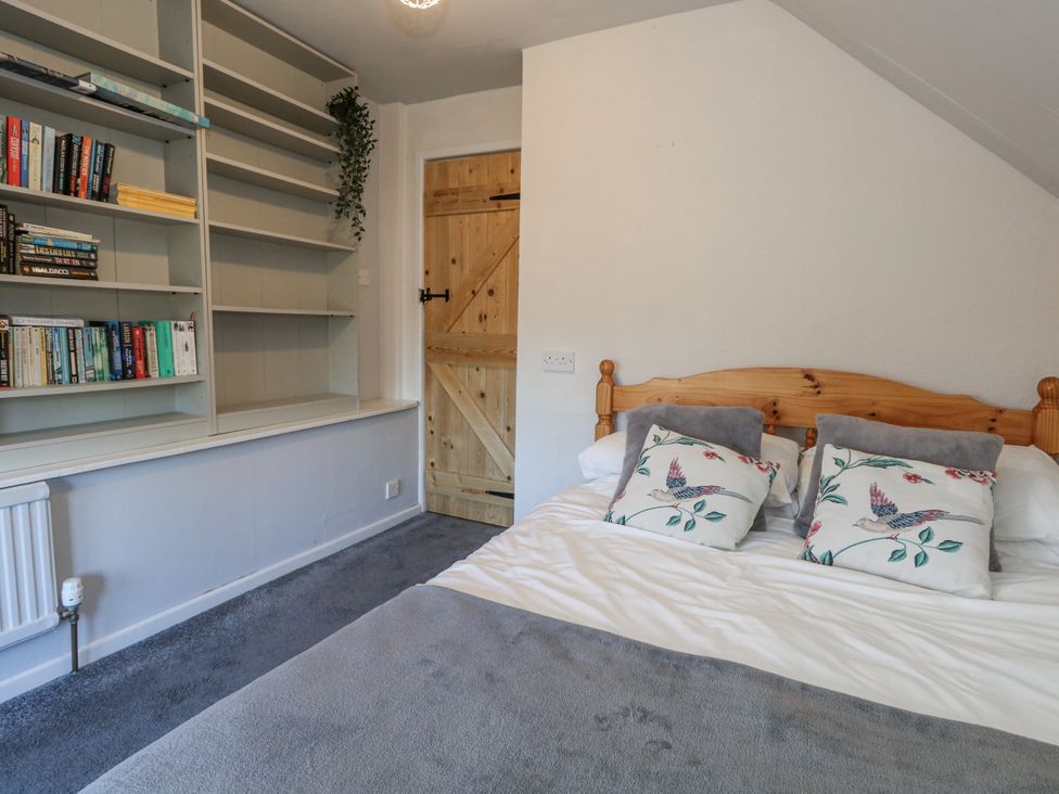 A bedroom with a bed and bookshelf at Honeysuckle Cottage in Smallridge Nr. Axminster