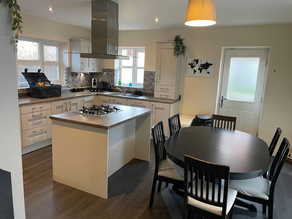 A kitchen with cabinets, kitchen island and dining table at 1 Oldridge Crescent Stockport