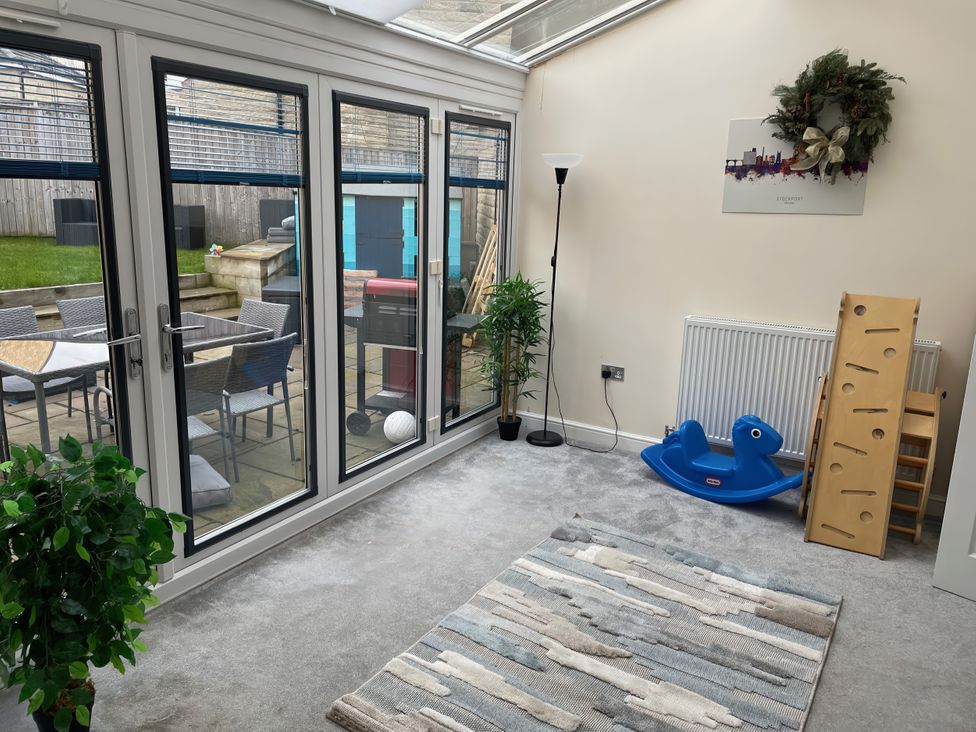 A conservatory with sliding glass doors and a toy slide at 1 Oldridge Crescent Stockport