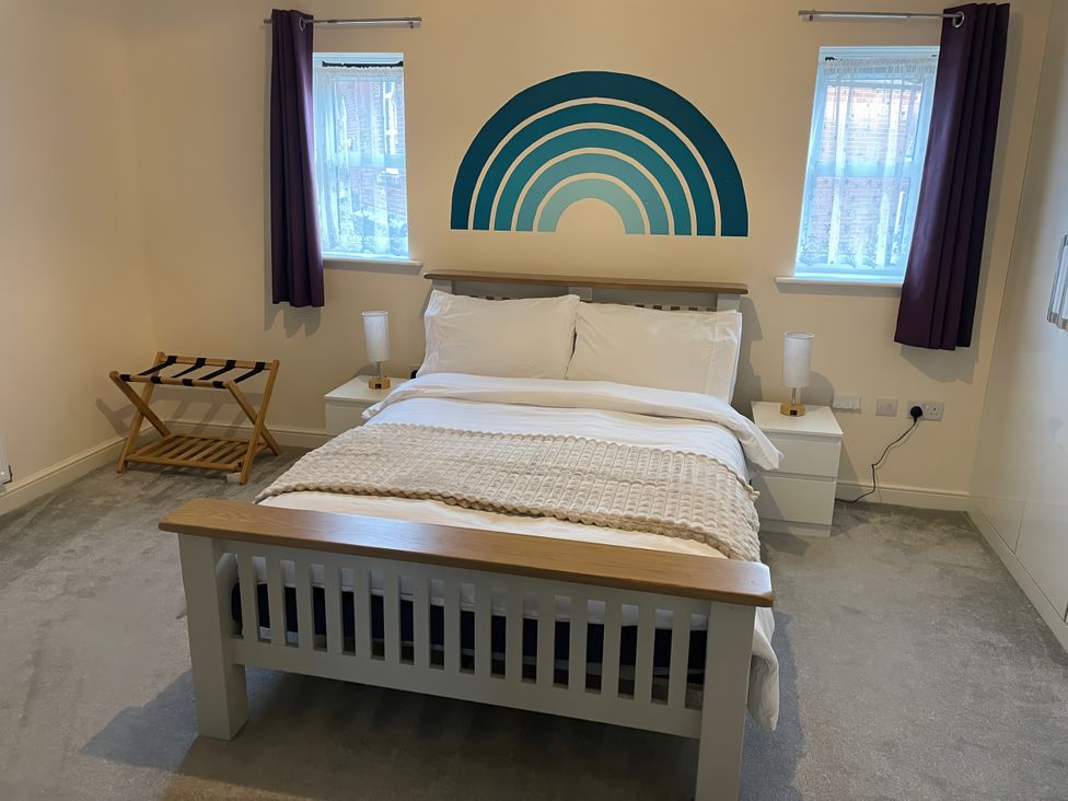 A bedroom with a bed and windows at 1 Oldridge Crescent in Stockport