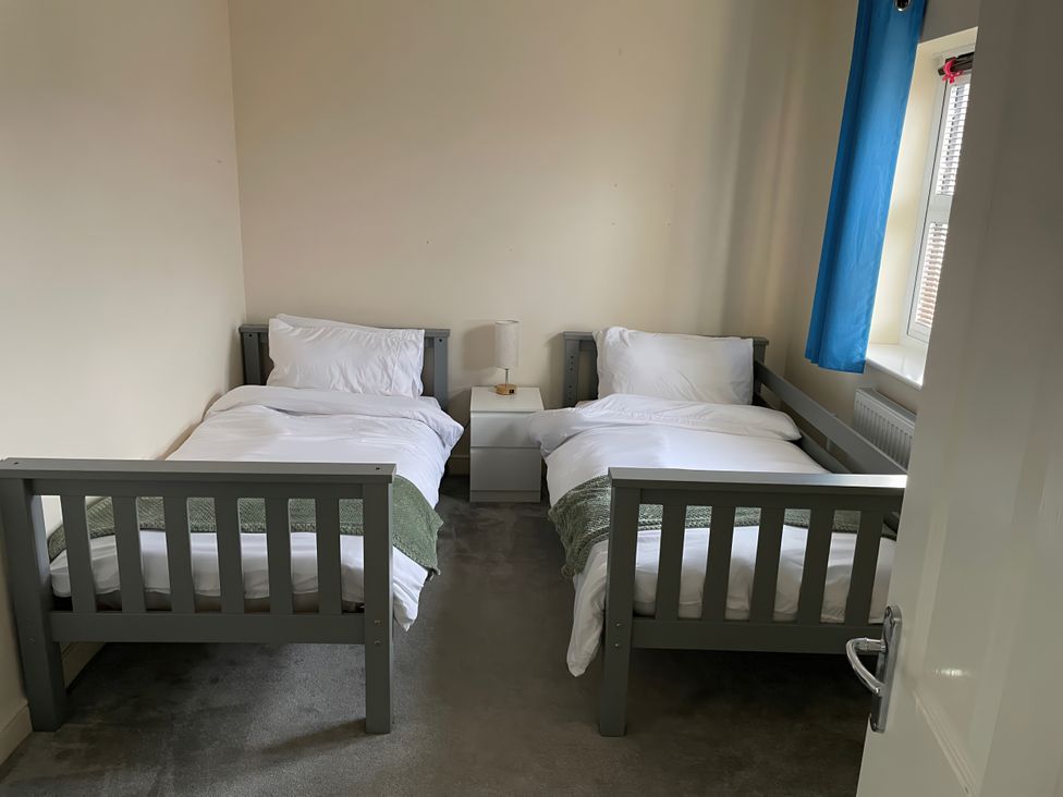 A bedroom with two beds and a bedside table at 1 Oldridge Crescent in Stockport