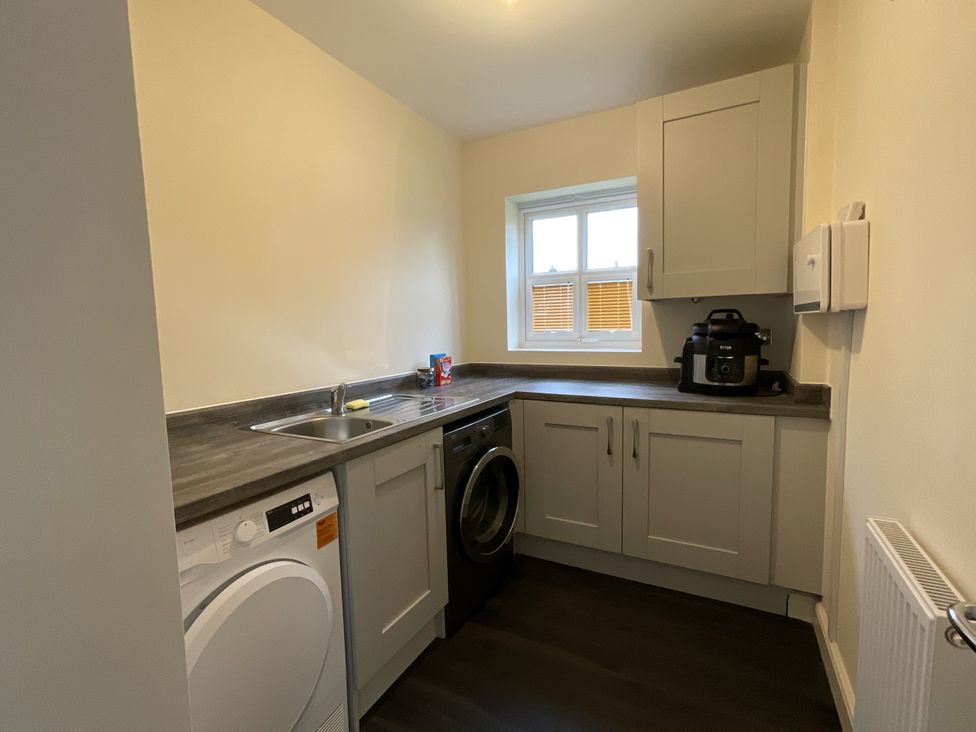 A kitchen with sink washing machine and dryer at The Winster in Marple Stockport