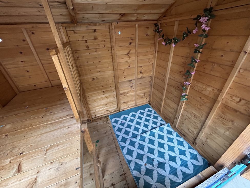 A wooden shed with a rug and decorative plants at The Winster, Marple, Stockport