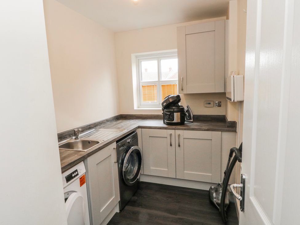 A kitchen with a washing machine, sink, and cooker at The Winster in Marple, Stockport