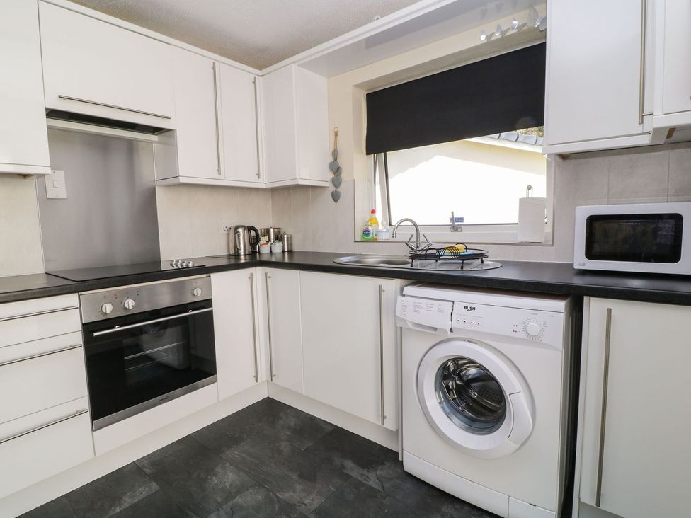 A kitchen with appliances including oven and washing machine at Willow Lodge Liskeard