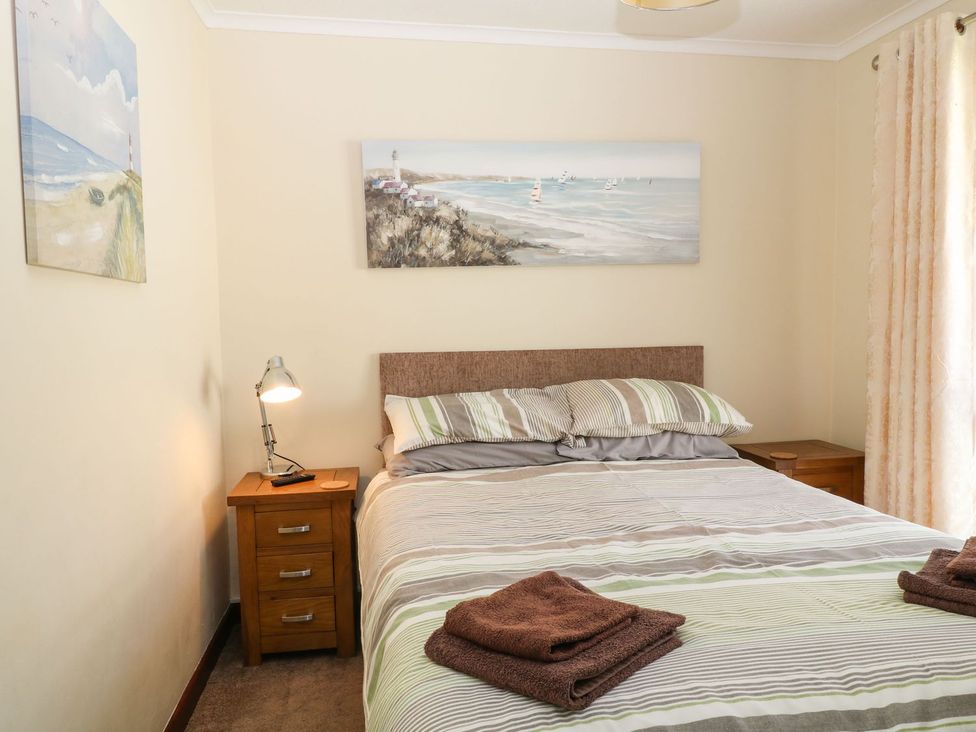 A bedroom with a bed and nightstand at Willow Lodge in Liskeard