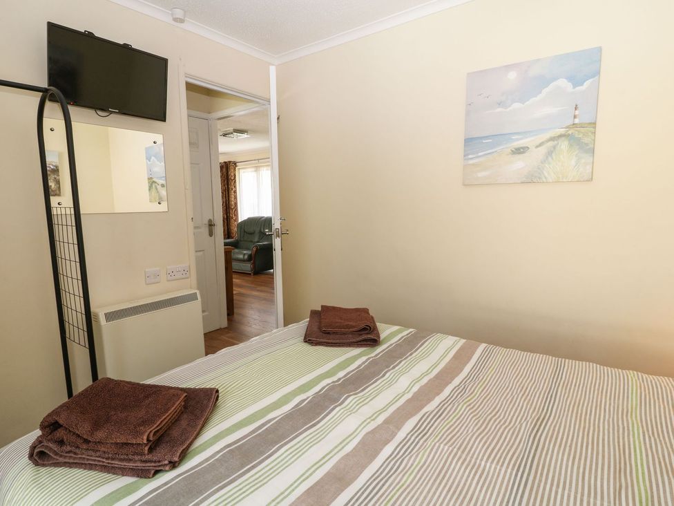 A bedroom with a bed and television at Willow Lodge in Liskeard