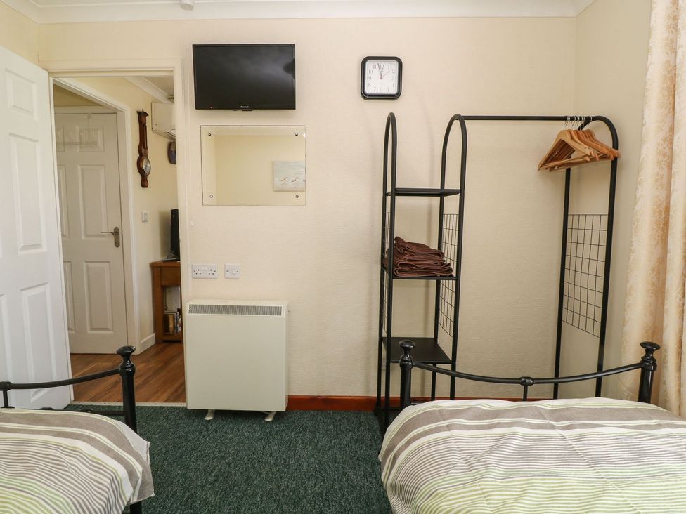 A bedroom with a television and clothes rack at Willow Lodge in Liskeard