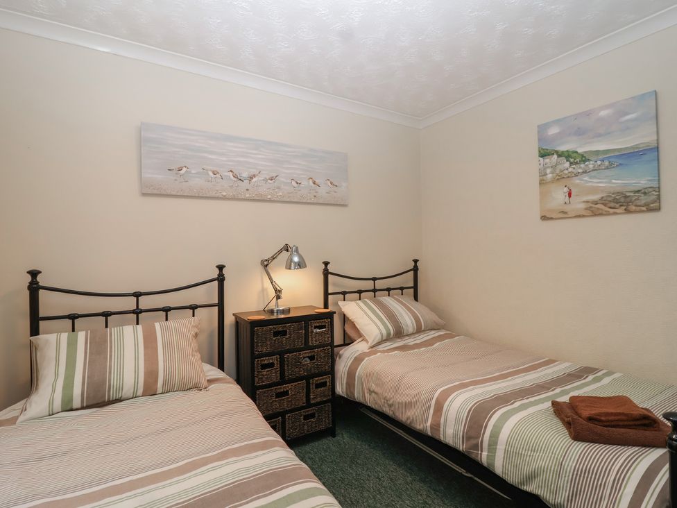 A bedroom with two beds and paintings on the wall at Willow Lodge near Liskeard