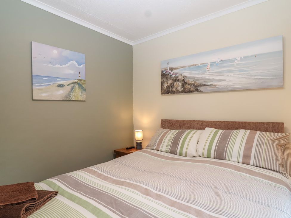 A bedroom with a bed and wall art at Willow Lodge Rosecraddoc Lodge near Liskeard