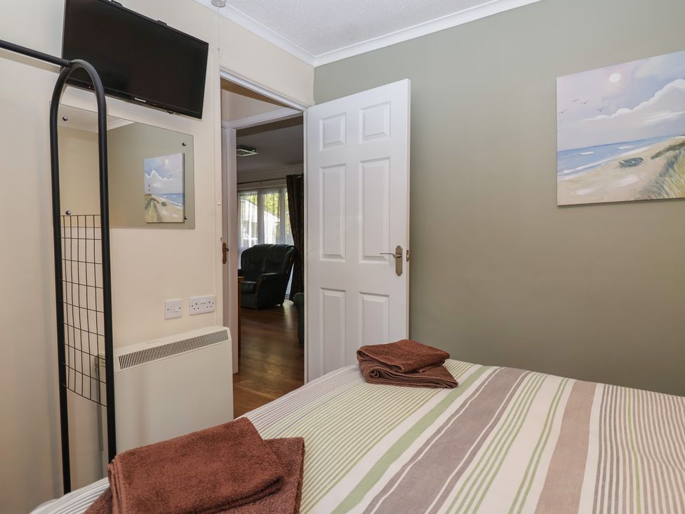 A bedroom with a television and mirror at Willow Lodge near Liskeard
