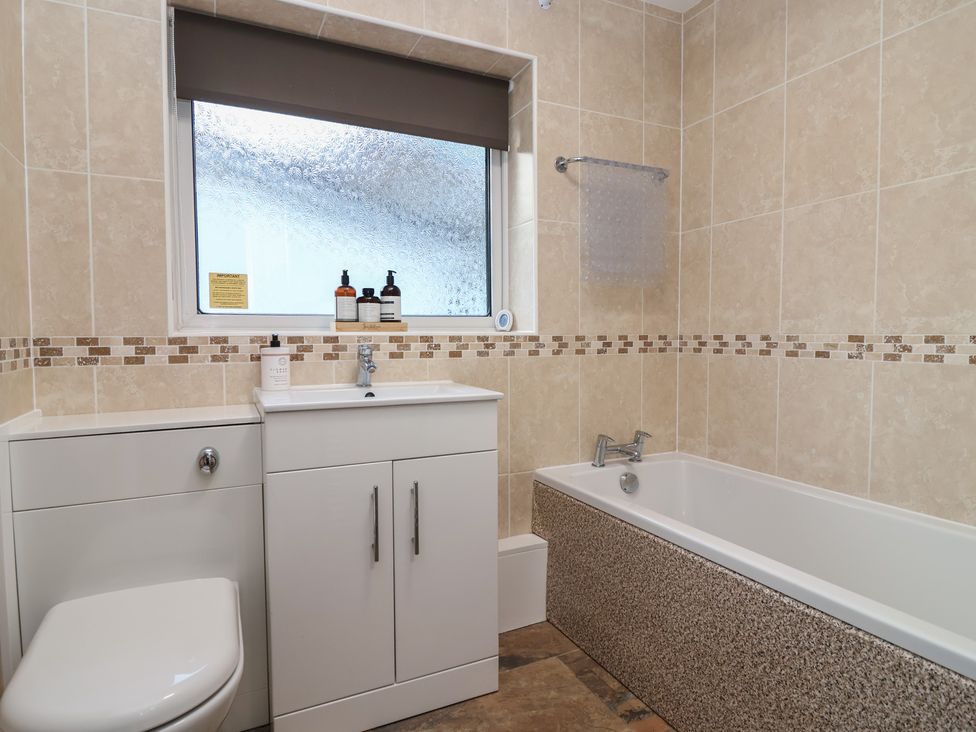 A bathroom with a bathtub and washbasin at Willow Lodge near Liskeard