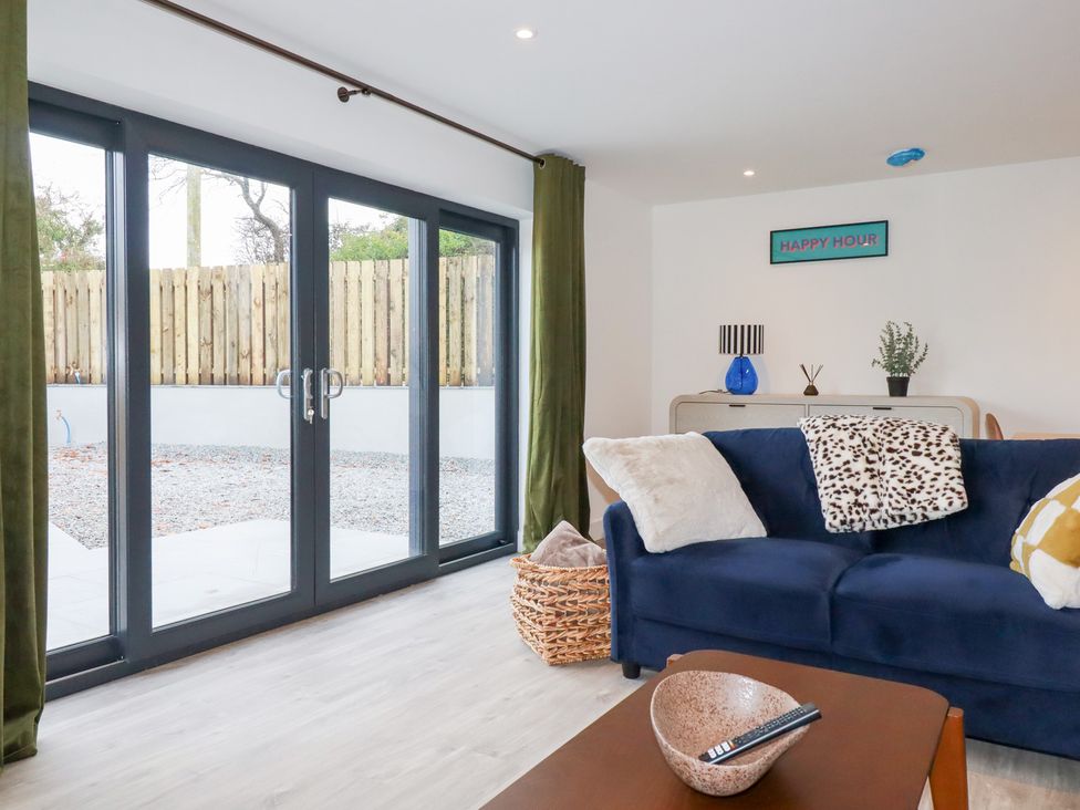 A living room with a blue sofa and glass doors leading to the outdoor area at Barn 5 
