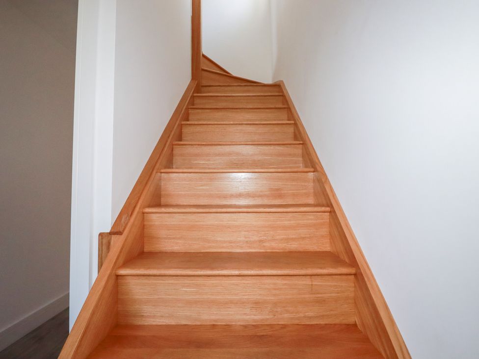 A staircase with wooden steps and a white wall at Barn 5