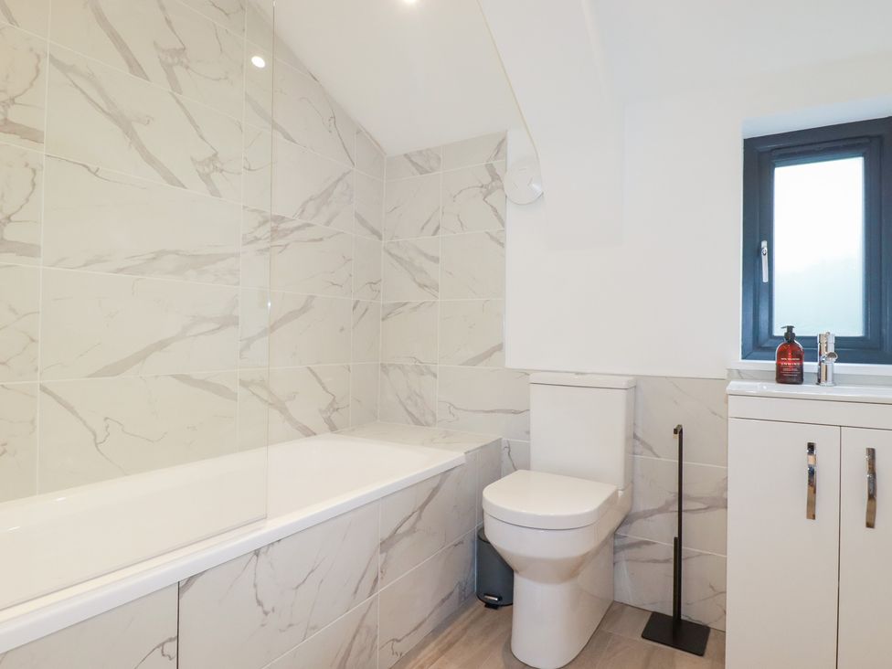 A bathroom with a bathtub, toilet, sink, and window at Barn 5
